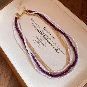 Elegant multi-layer necklace with white pearls, purple crystals, and gold chains