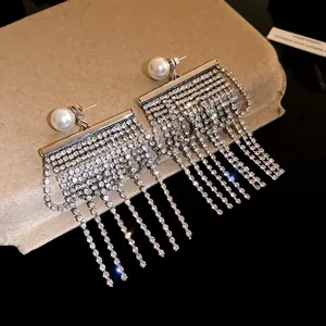 Détail de boucles d'oreilles perles avec de longs glands en strass scintillants