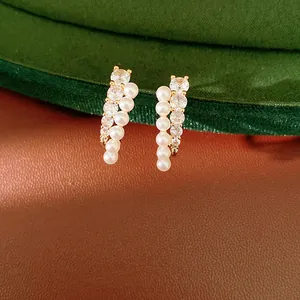 Close-up of elegant gold-tone earrings with vertical rows of pearls and clear crystals