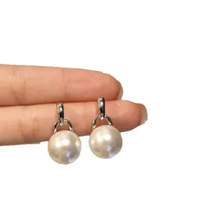 Eleganti orecchini pendenti con perle argentate in stile francese tenuti con la mano