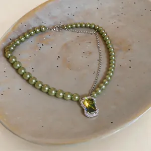 Detail showing green pearl necklace with a brilliant emerald green zircon pendant on a tray