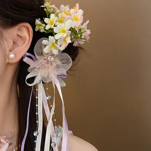 Close-up detail of a romantic floral hair clip with mesh petals and ribbon tassels