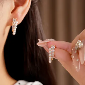 Close-up of elegant double-row earrings featuring white pearls and sparkling zircons.