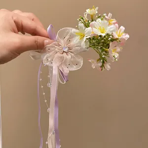 Detail of a Mori-style hair clip featuring pastel fabric flowers and flowing ribbons