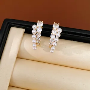 Close-up detail of elegant gold-tone earrings featuring rows of white pearls and sparkling cubic zirconia.