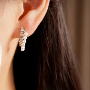 Close-up detail of elegant silver needle earrings with zirconia and white pearls