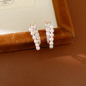 Elegant curved stud earrings featuring white pearls and sparkling cubic zirconia