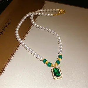 Vintage pearl necklace featuring a large emerald-cut green gemstone pendant and gold accents