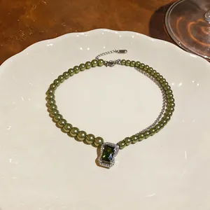Close-up of vintage green beaded pearl necklace with a large emerald-cut zircon pendant