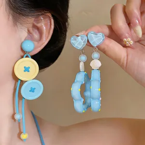 Primer plano de pendientes colgantes de corazón y concha azul estilo dopamina