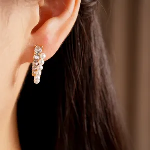 Close-up of elegant gold-plated curved stud earrings featuring pearls and zirconia stones