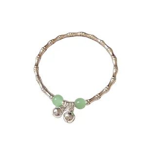 Elegant silver bamboo joint bracelet featuring light green beads and dangling bells on white background