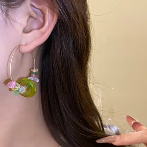 Detailaufnahme bunter Creolen mit Stein- und Glasperlen am Ohr eines asiatischen Models