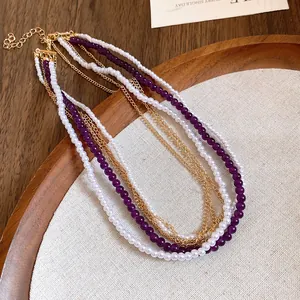 Detailed view of multi-layered necklace with white pearls, purple beads and gold chains