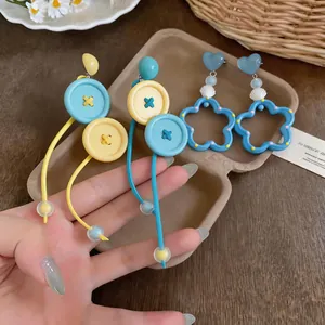 Detalle de pendientes estilo dopamina con colgantes de corazón y concha en azul y amarillo.