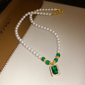 Detailed macro view of vintage pearl necklace featuring a large emerald green zircon pendant.