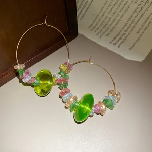 Nahaufnahme von bunten Stein- und Glasperlen auf kunstvollen goldenen Creolen