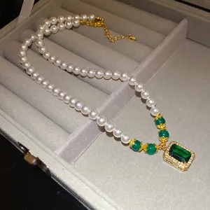 Close-up of a vintage pearl necklace featuring an emerald green rectangular pendant