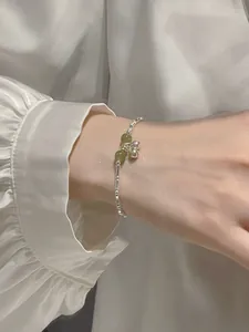 Close-up detail view of a silver bamboo joint bracelet featuring green beads and bells