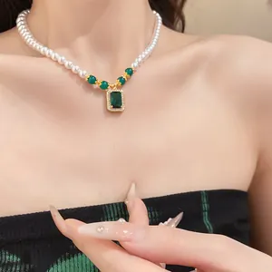 Close-up detail of a vintage style pearl necklace with an emerald green square pendant