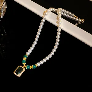 Detail of vintage pearl necklace with square green zircon pendant and gold accents.
