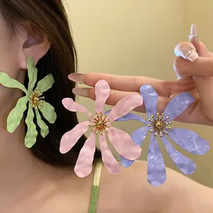 Close-up showing oversized matte flower earrings in pastel green pink and purple