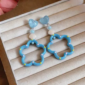 Vista detallada de pendientes estilo dopamina azul con conchas y colgantes flores