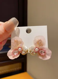 Close-up detail of elegant pink resin flower stud earrings featuring pearls and crystals