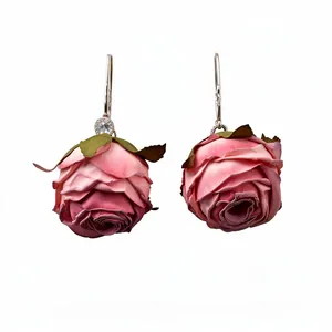 Eleganti orecchini a goccia in tessuto rosa a forma di bocciolo su uno sfondo bianco
