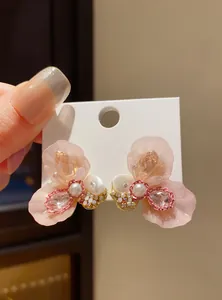Detailed view of elegant pink resin flower earrings with pearls and shimmering crystals
