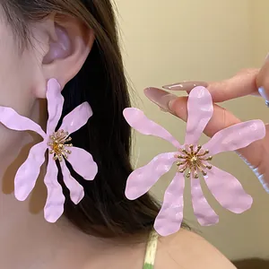 Close-up view of oversized pink flower earrings with delicate gold stamen detail