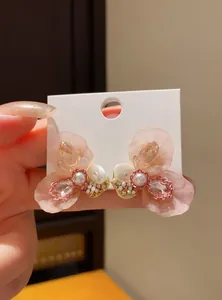 Close-up of elegant pink resin flower earrings with pearls and shining crystals on card