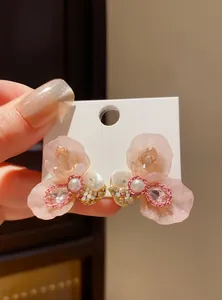 Detailed close-up showing pink resin flower earrings featuring pearl and sparkling rhinestones