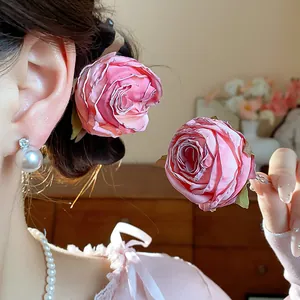 Dettaglio di un elegante fermaglio per capelli con rosa in tessuto rosa.