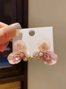 Macro view of pink resin flower stud earrings with pearls and rhinestones