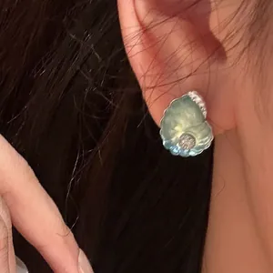 Makroansicht eines eleganten Muschelohrrings aus Harz mit funkelnden Zirkonen.
