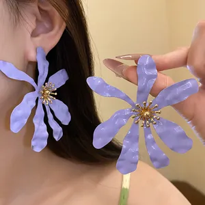 Macro view of exaggerated purple flower earrings with gold stamens and irregular petals