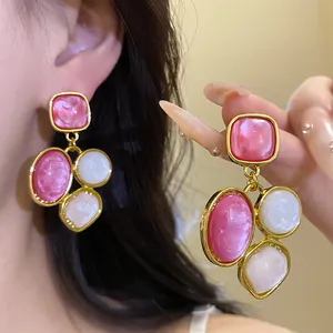 Dettaglio di orecchini vintage in resina con pietre rosa e bianche.