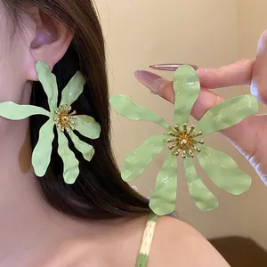 Macro detail of oversized light green flower earrings worn for a fresh summer style