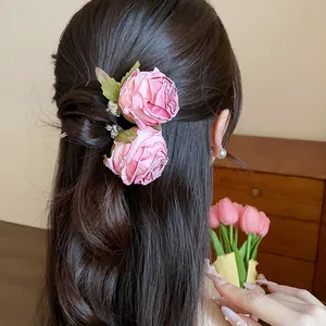 Dettaglio di un elegante fermaglio per capelli con rosa in tessuto rosa su uno chignon
