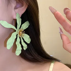 Macro view of oversized light green flower earring with detailed golden center.