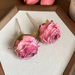 Dettaglio ravvicinato di due eleganti forcine a forma di rosa di stoffa rosa su vassoio.