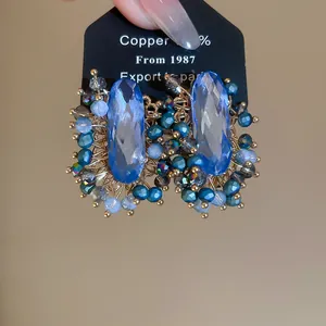 Detail view of vintage oval blue crystal earrings with intricate beadwork and copper base.