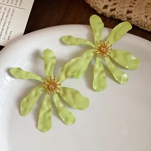 Detail view of oversized lime green flower earrings for a sweet vacation style look.