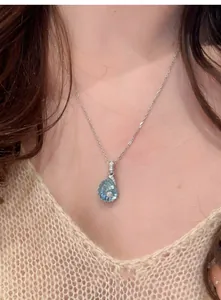 Detailaufnahme einer eleganten Muschel-Halskette mit blauem Harz und winzigen Zirkonen