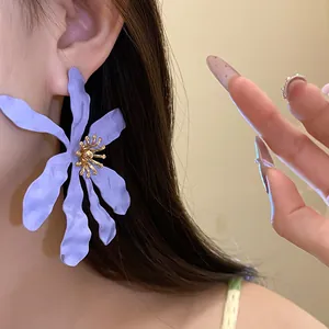 Large purple flower earring with matte petals and golden stamen detail worn by model