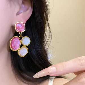 Primo piano di orecchini pendenti vintage in resina con cabochon rosa e bianchi