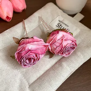 Dettaglio di forcine per capelli con rose in tessuto rosa su astuccio in tela e fiori
