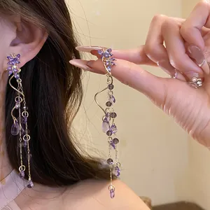 Detail of purple butterfly tassel earrings with teardrop crystals and gold chains