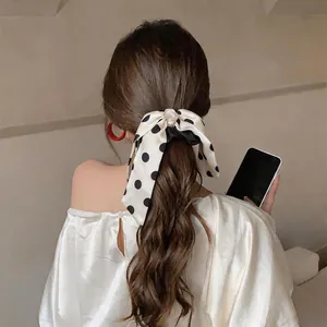 Close-up of a French style polka dot bow scrunchie with ribbons in a ponytail.